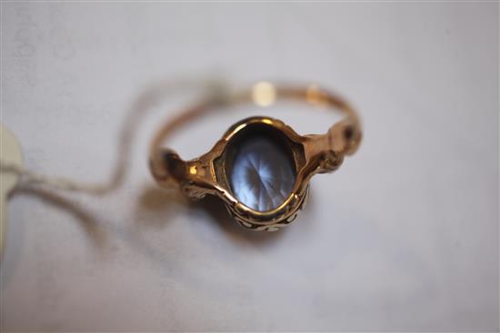 A yellow metal ring set oval sapphire in scrolled mount between seated lion shoulders, size T.